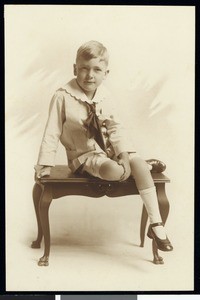 A portrait of a boy sitting on a small wooden table