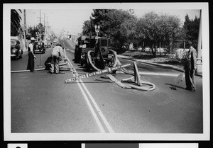 Workers from the Department of Public Works cleaning a swer using a portable Barnes pump over a manhole