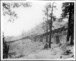 Train passing through a railroad snow shed and onto a tressel in the mountains at Cisco, ca.1910