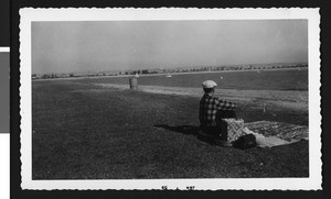 Man sitting by the water on Mission Bay, January 1959