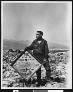 Man posing next to a sign in Death Valley, ca.1900-1950