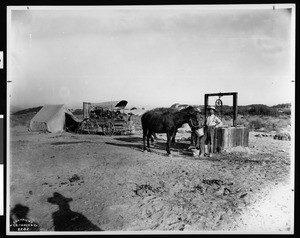 Group of people with a covered wagon and tent at Indian Wells on the Butterfield Stage Line east of Palm Springs and west of Indio, ca.1903-1904