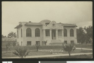 Exterior view of a public library with young palm trees in Woodland, 1900-1940