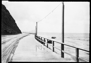 Wooden walkway along the shore, showing dirt road to the right, Catalina Island, November 11, 1927