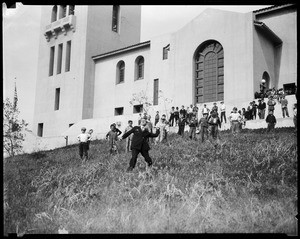 Few dozen children watching a man throw an object