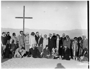 Group of people posed in front of a cross at a funeral in the desert