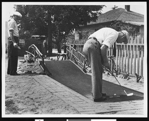 A man putting on a miniature golf course, ca.1930