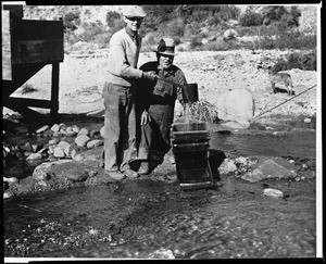 Portrait of J.W. Vernon and Chas. Chanser sifting for gold on a river bank, Plymouth, ca.1932