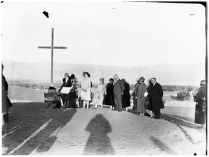 People gathered around a cross for a funeral in the desert