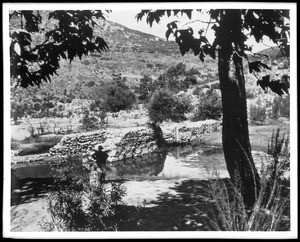 Figure standing at the edge of the dam of Mission Gorge, 1936