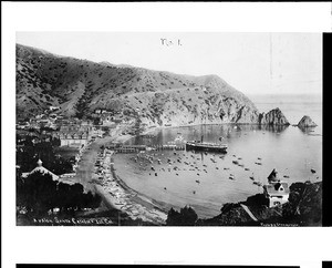 Aerial view of Avalon Harbor on Catalina Island showing a fleet of small boats in the water and on the beach, ca.1905