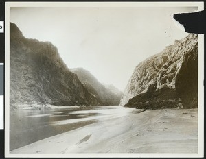 Unidentified river making its way between two cliff faces, showing sandy banks at right, ca.1950