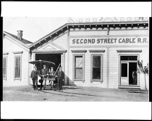 Exterior view of the car barn for the Second Street Cable Car system in Los Angeles, showing a group of uniformed conductors, ca.1890