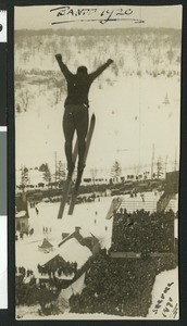 Ski jumper soaring above a crowd of spectators at Banff by R.J. Verne, 1920