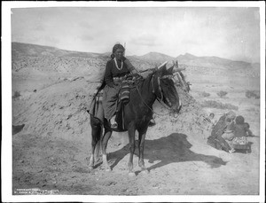 Navajo Indian maiden on a pony in front of a hogan, ca.1901