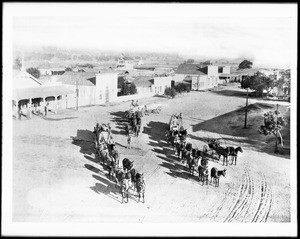 Aerial view of Newhall showing mule teams and a horse-drawn carriage, 1885