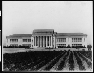 Exterior view of an unknown school with crops in front