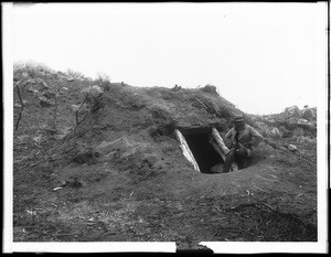 Man sitting at entry to Indian dug-out home on Warner's Ranch, ca.1901