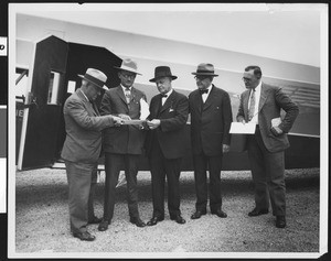 Five men looking over a map near a plane, ca.1930