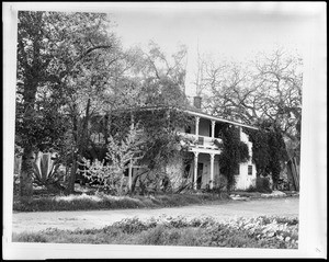 Exterior view of the Miguel Leonis adobe from a nearby dirt road, 1962