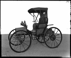 View of a 1901-model Victor automobile in a parking lot near a Safeway store(?), ca.1935