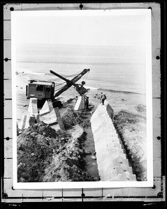 Crane moving concrete blocks into place to build up the Southern California shoreline
