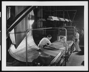 Factory workers putting sheets of rubber into a machine, ca.1945