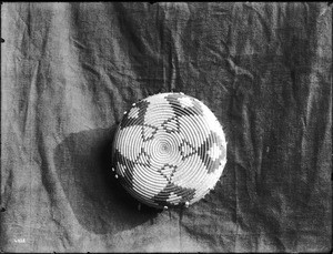 Indian basket displayed in front of a cloth backdrop, ca.1900