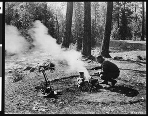 A man cooking over a campfire near the Lolo National Forest, Montana, January 7, 1931
