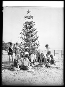 Group of women posing with a man dressed as Santa Claus on a beach