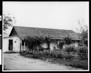 Exterior view of the "Adobe Casa of Dona Polonia Montanez", showing a patchwork roof, San Juan Capistrano, ca.1930