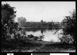 Oakland's Lake Merritt and homes and buildings nearby, showing trees in the foreground, ca.1910