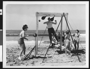 Men and women using punching bags on Venice beach, ca.1940