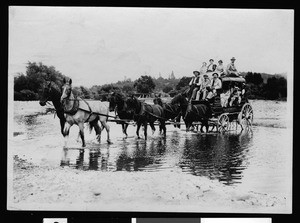 Stagecoach loaded with people crossing a river in Lake County, ca.1910