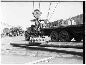 Steel pipe being loaded on to a truck with a large magnet at the Los Angeles Harbor, 1930