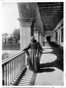 Franciscan monk in the exterior front corridor overlooking the garden at Mission Santa Barbara, ca.1904