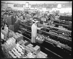 Interior view of Imperial Super Market showing a woman with a grocery basket shopping, Vermont Avenue and 6th Street, May 10, 1941