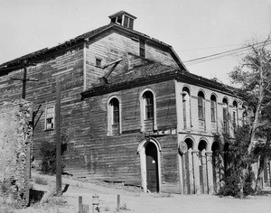 Exterior view of the Pipers Opera House in Virginia City, Nevada, showing fire hydrant and crumbling brick wall, ca.1935