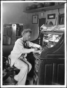 Portrait of a Charles F. Lummis sitting and writing at a roll-top desk, ca.1902