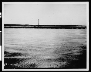 Flooded Los Angeles River flowing under a Pacific Electric Railway bridge, 1916