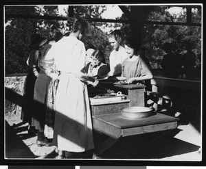 Campers dishing up food in a pavilion, ca.1910