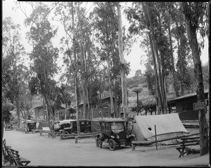 View of a camping resort, showing cabins, tents and automobiles, ca.1925