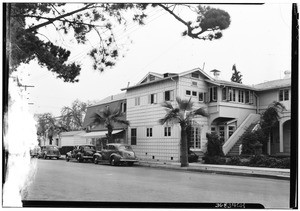 Row of automobiles parked on a street in front of a strip of houses