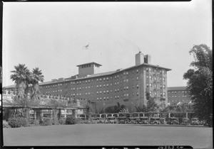 Exterior view of the Ambassador Hotel in Los Angeles with a parking lot in the foreground, ca.1920-1929