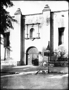 East entrance of Mission San Gabriel with El Camino Real bell, ca.1908