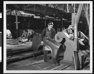 Interior view of an unidentified automobile factory showing workers on an assembly line, ca.1925