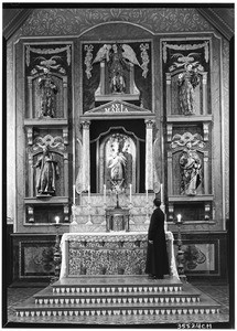 Interior view of the San Gabriel Mission, showing a priest at the altar