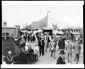 View of the entrance to the Los Angeles County Fair in Pomona, showing fairgoers and a large canvas-topped tent, ca.1925-1929