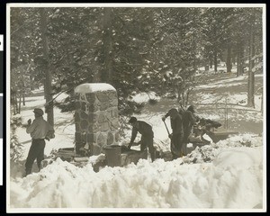 People shoveling snow out of a campsite and preparing a campfire at Big Pines Camp, ca.1930