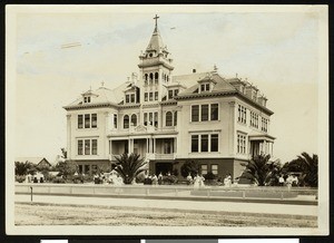 Exterior view of the Moreland Notre Dame Academy in Watsonville, showing women gathered on the lawn, ca.1900